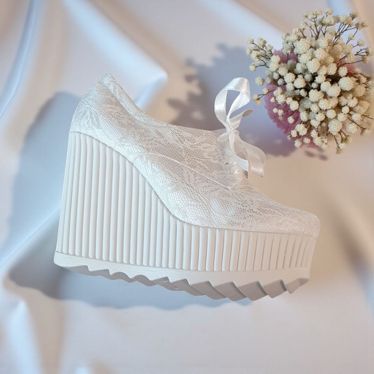 White lace-up shoe with a thick sole on a light background