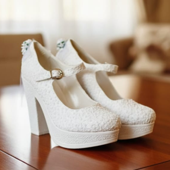 White lace high-heeled shoes on a wooden table with a blurred background