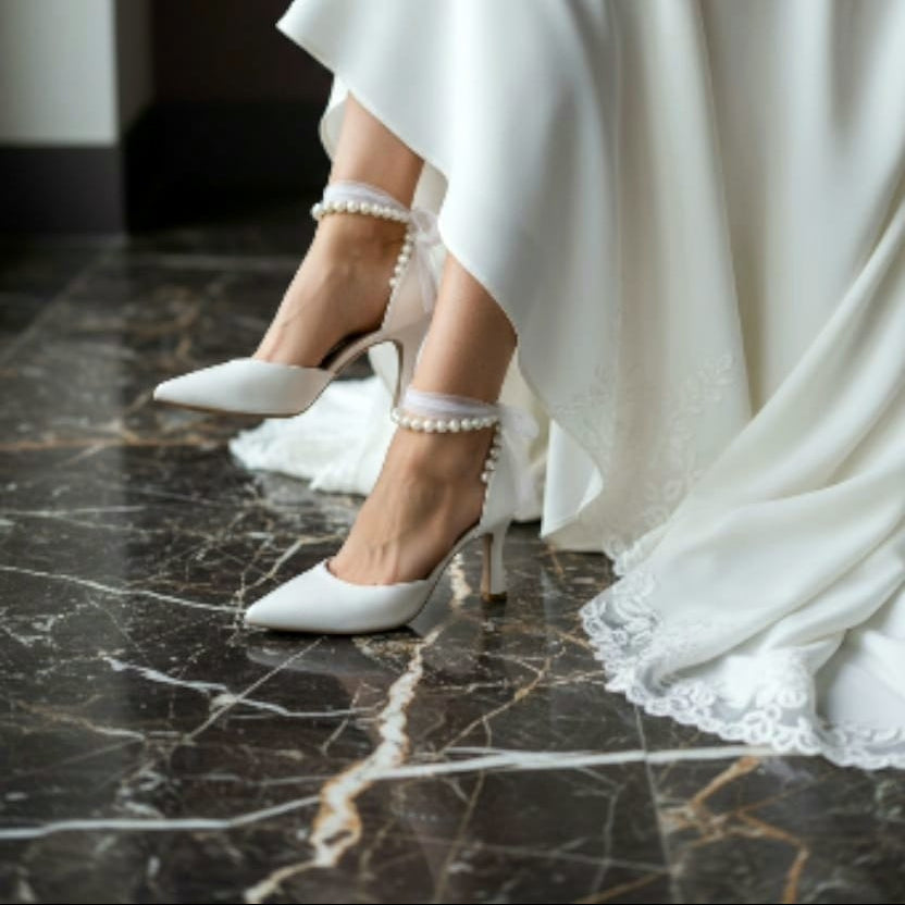 White wedding dress with high-heeled shoes on a marble floor