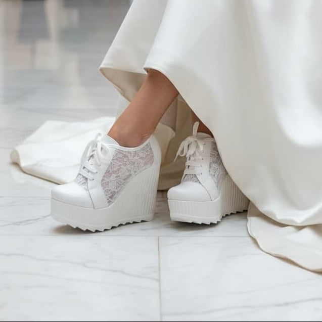 Person wearing a white dress with white platform shoes in an indoor setting.