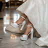 White wedding shoes worn by a bride in an elegant indoor setting.