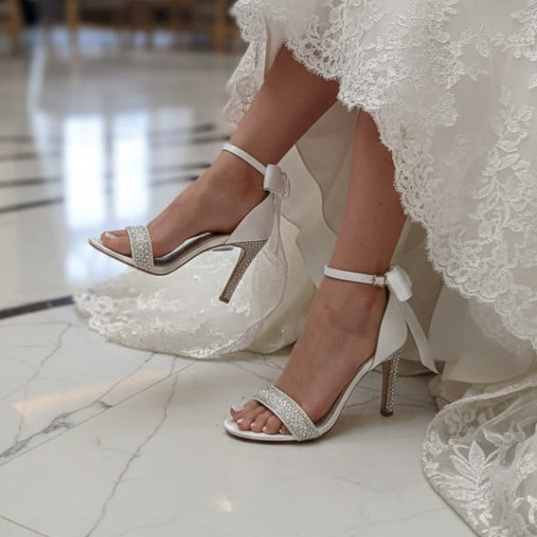 White wedding dress with lace details and Bridal high-heeled shoes on a marble floor.